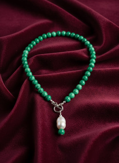 Green beaded necklace with a pendant on a dark red background