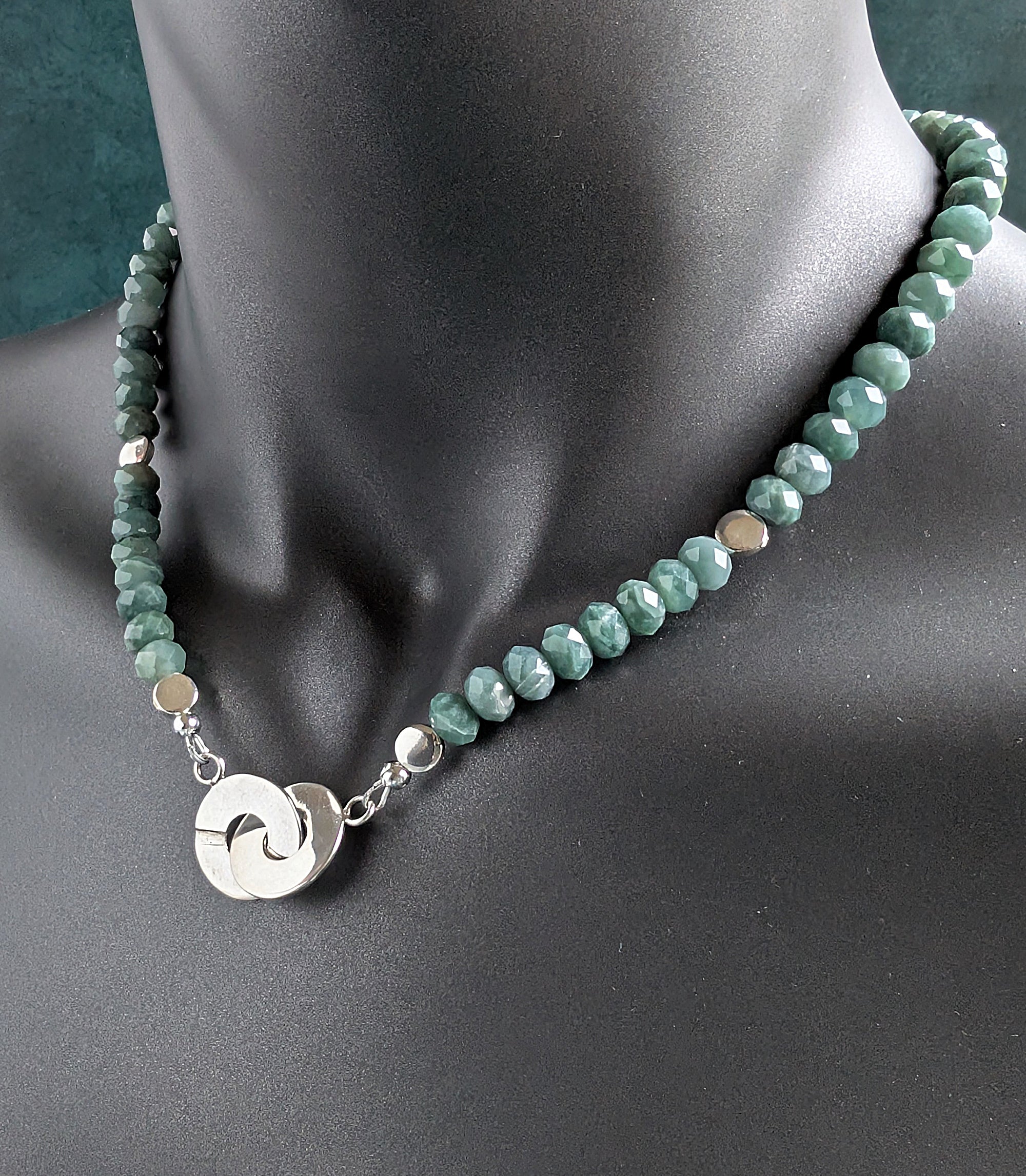Necklace with green beads and a silver pendant on a mannequin.