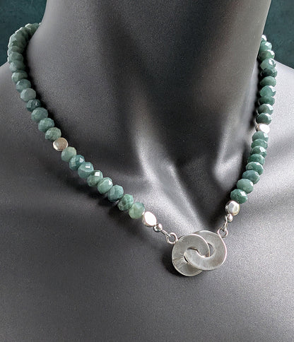 Necklace with green beads and a silver pendant on a mannequin.