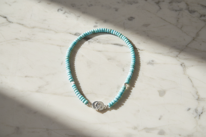 Necklace with light blue beads and a silver clasp on a white marble background