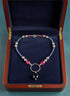 Necklace with blue, rose, and navy beads on a  navy background in a wooden jewelry case.