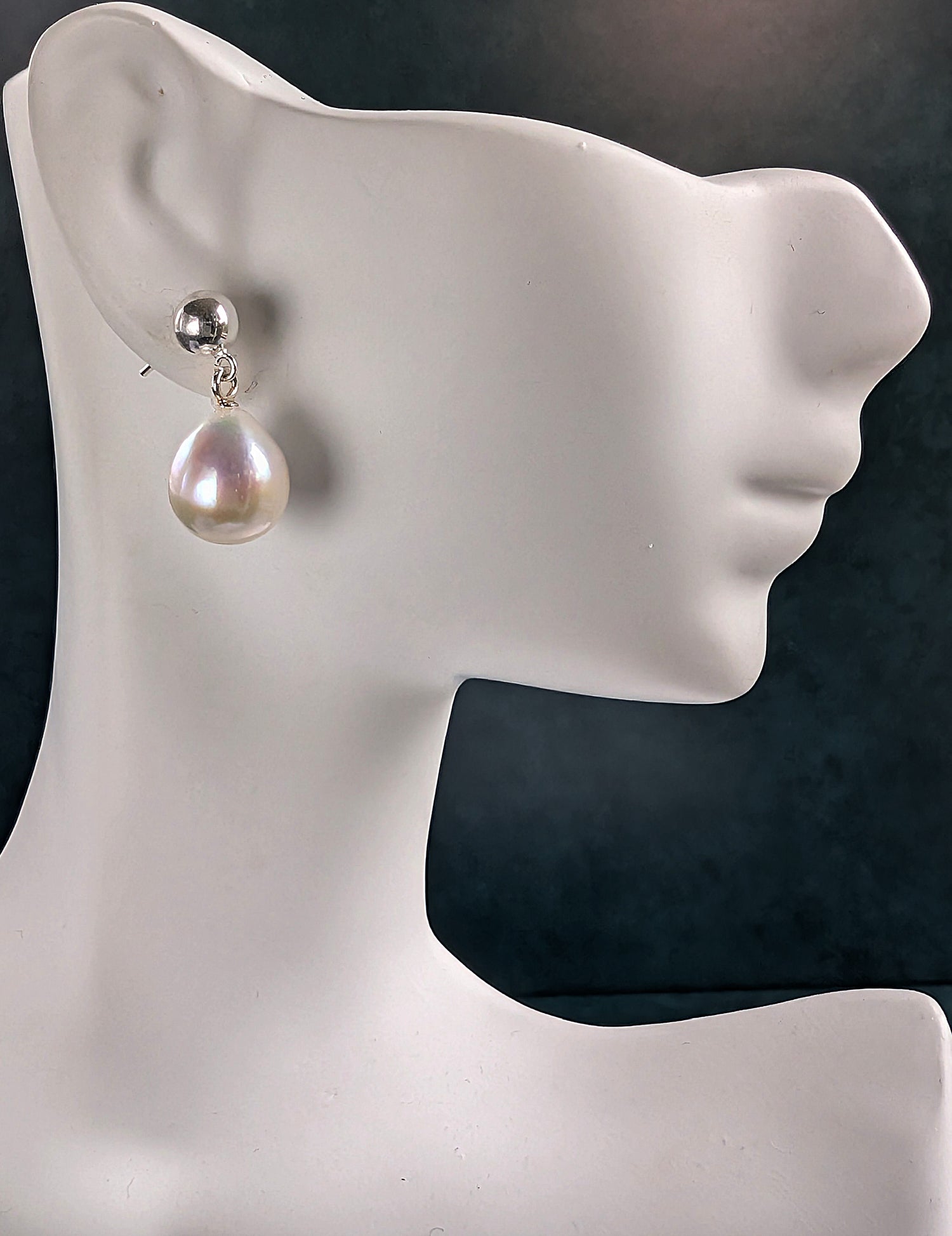 Pearl earring on a mannequin ear with a dark background