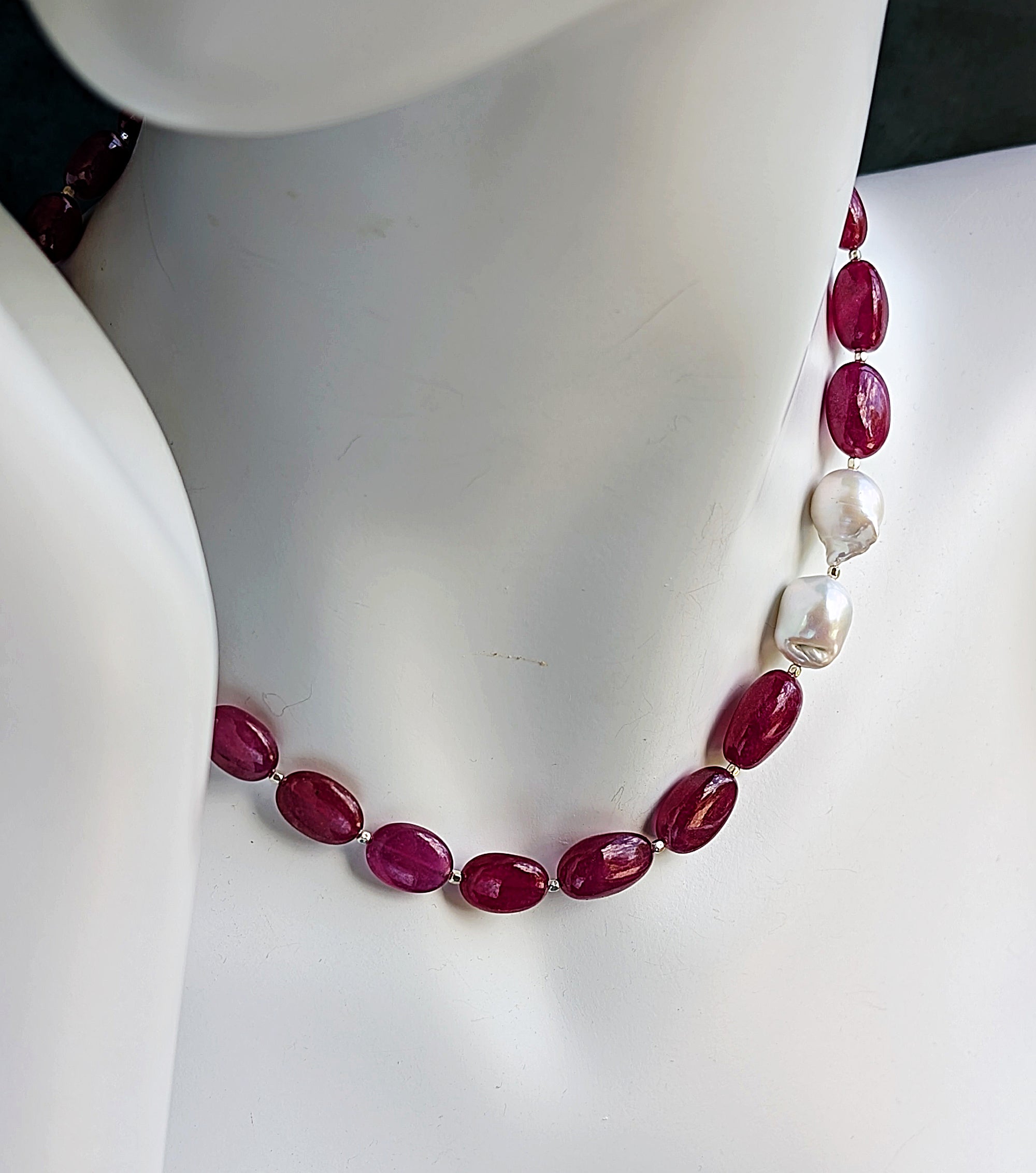 Cabochon rubies with two brooch like baroque pearls on a mannequin neck.