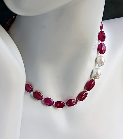 Cabochon rubies with two brooch like baroque pearls on a mannequin neck.
