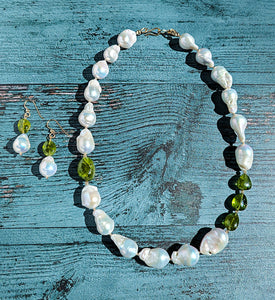 Baroque pearl, peridot and gold  necklace measuring 19". The peridots are offset with three on one side of the necklace and one larger peridot on the opposite side. Between each pearl and peridot gem are 14 Karat gold beads and the necklace is finished with a 14 Karat hook and eye clasp. Matching dangle earrings are also pictured with the necklace. 