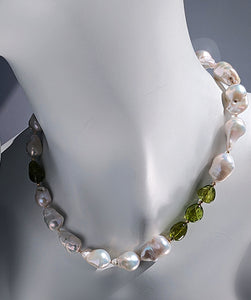 Baroque pearl, peridot and gold necklace measuring 19". The peridots are offset with three on one side of the necklace and one larger peridot on the opposite side. Between each pearl and peridot gem are 14 Karat gold beads. The necklace is pictured on a life size mannequin neck.