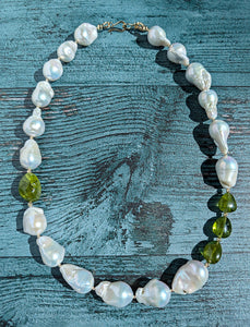 Baroque pearl, peridot and gold necklace measuring 19". The peridots are offset with three on one side of the necklace and one larger peridot on the opposite side.  Between each pearl and peridot gem are 14 Karat gold beads and the necklace is finished with a 14 Karat hook and eye clasp.