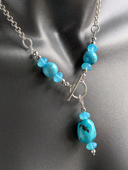 Turquoise bead and silver toggle necklace on a black mannequin.
