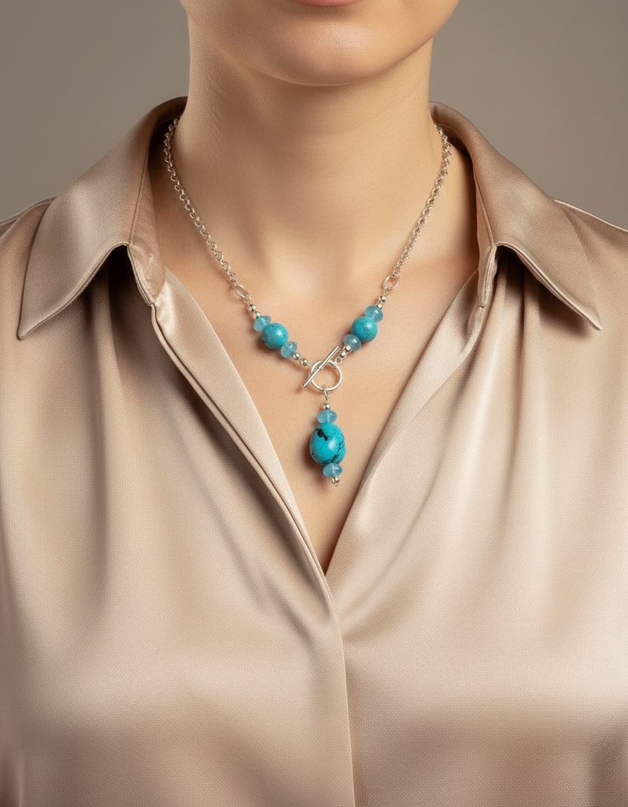 Necklace with turquoise beads on a model wearing a mauve silk blouse.