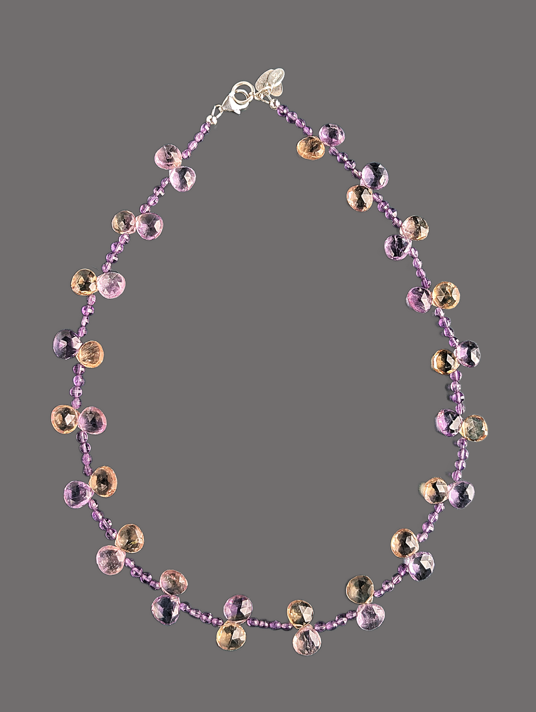 Necklace with purple and gold beads on a gray background