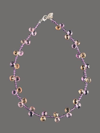 Necklace with purple and gold beads on a gray background
