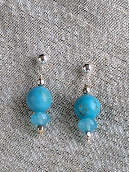 Pair of earrings with blue beads and silver accents on a textured gray background