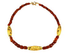 Load image into Gallery viewer, Necklace with three gold gilded oblong lava beads evenly spaced between pecan colored amber beads laid out in a circle with closed toggle clasp.
