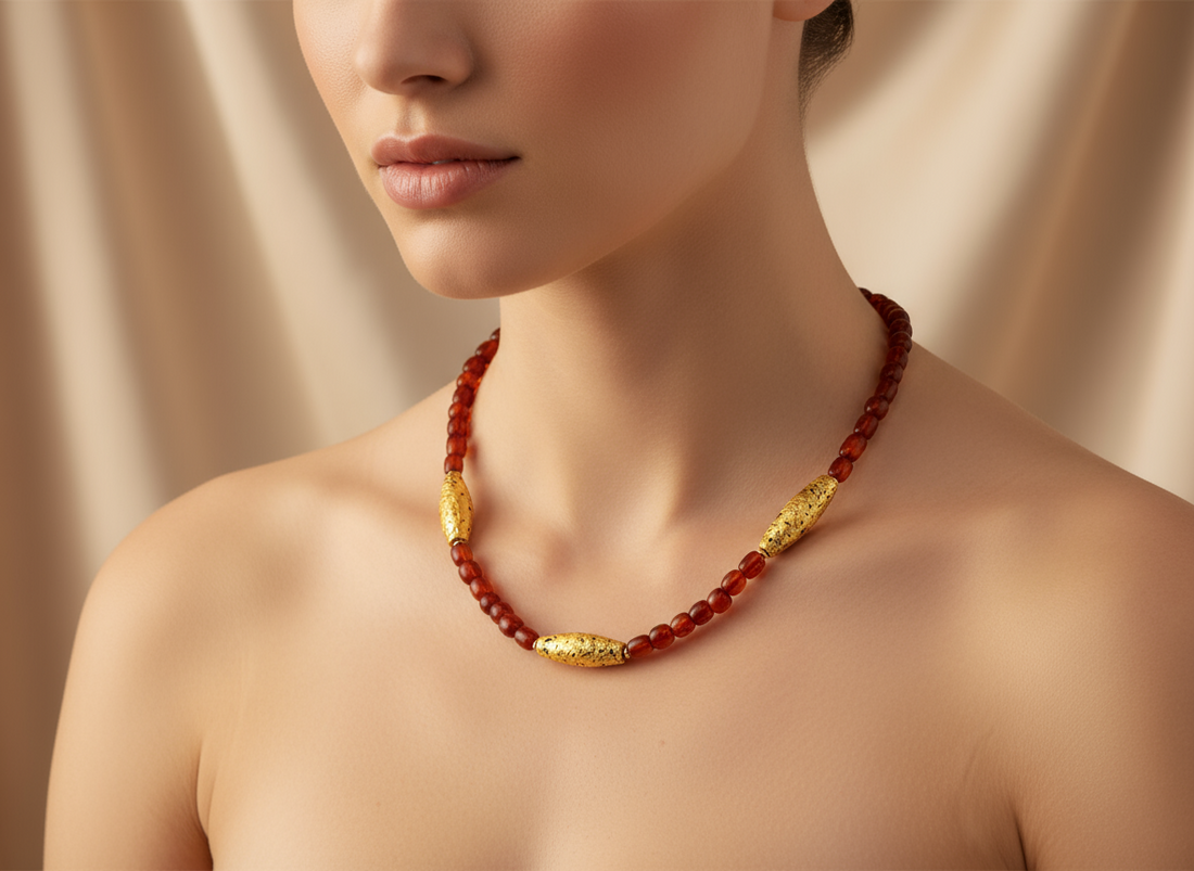 Necklace with three gold gilded oblong lava beads evenly spaced between pecan colored amber beads on a models neck.