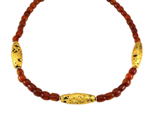 Load image into Gallery viewer, Necklace with three gold gilded oblong lava beads evenly spaced between pecan colored amber beads laid out in a circle close up.