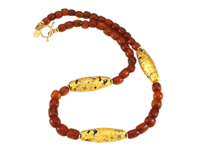Necklace with three gold gilded oblong lava beads evenly spaced between pecan colored amber beads with 14 karat gold filled toggle clasp and artist signature tag.