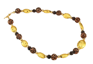 Hand made necklace with 23 karat gold gilded lava stones, lamp work bronze Czech glass, and 14 karat gold filled small round beads. The necklace is finished with 14 karat gold filled toggle clasp. Necklace is facing to the right.