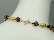 Load image into Gallery viewer, Hand made necklace with 23 karat gold gilded lava stones, lamp work bronze Czech glass, and 14 karat gold filled small round beads. The necklace is finished with 14 karat gold filled toggle clasp. The necklace is photographed on a white mannequin&#39;s neck showing the toggle clasp.