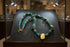 Green turquoise and gold necklace in a display case on a black background.