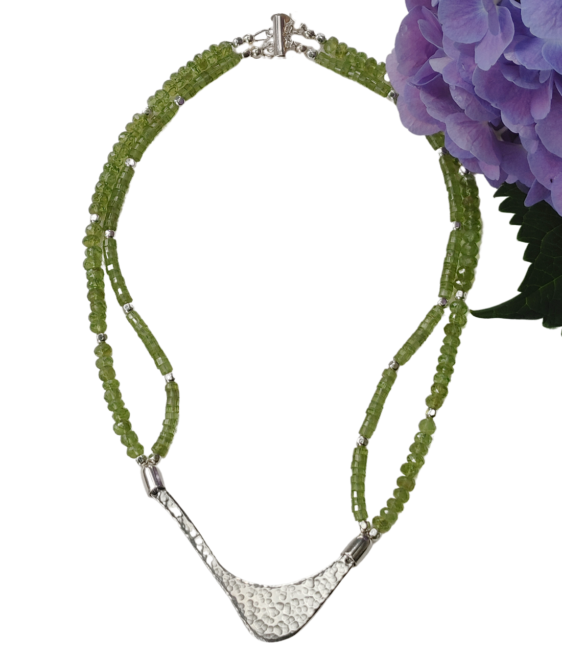 Hammered silver abstract pendant necklace with two strands of peridot and silver beads. The necklace is finished with a magnetic clasp and the artist&