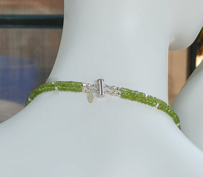 Hammered silver abstract pendant necklace with two strands of faceted peridot and silver beads. The necklace is finished with a magnetic clasp and the artist&