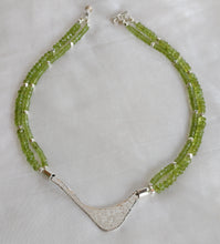 Load image into Gallery viewer, Hammered silver abstract pendant necklace with two strands of peridot and silver beads. The necklace is finished with a magnetic clasp and the artist&#39;s signature tag. The necklace measures 17&quot; (43.18cm). The necklace is displayed, in full, on a white background