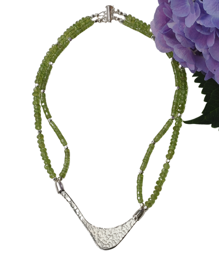 Hammered silver abstract pendant necklace with two strands of peridot and silver beads. The necklace is finished with a magnetic clasp and the artist's signature tag. The necklace measures 17