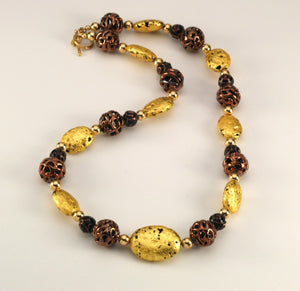 Hand made necklace with 23 karat gold gilded lava stones, lamp work bronze Czech glass, and 14 karat gold filled small round beads. The necklace is finished with 14 karat gold filled toggle clasp. 