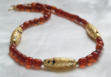 Load image into Gallery viewer, Necklace with three gold gilded oblong lava beads evenly spaced between pecan colored amber beads.