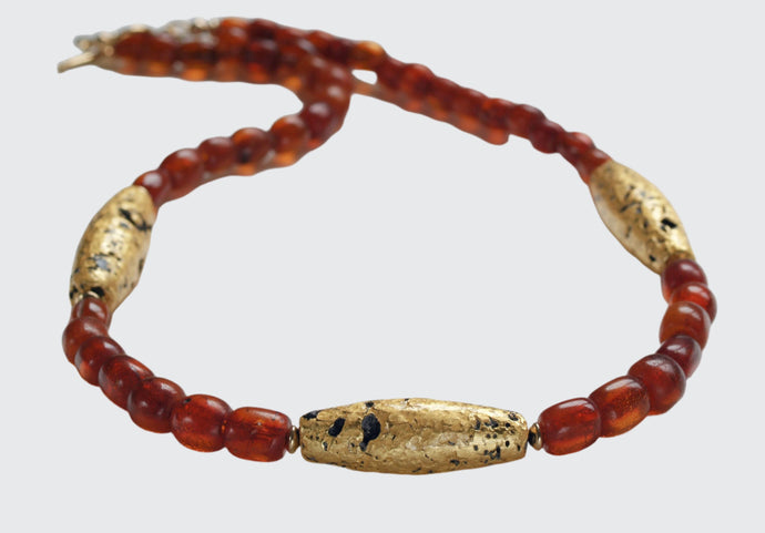 Necklace with three gold gilded oblong lava beads evenly spaced between pecan colored amber beads.