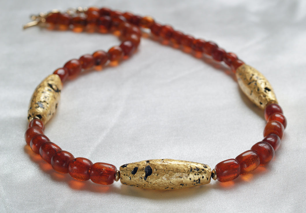 Necklace with three gold gilded oblong lava beads evenly spaced between pecan colored amber beads.